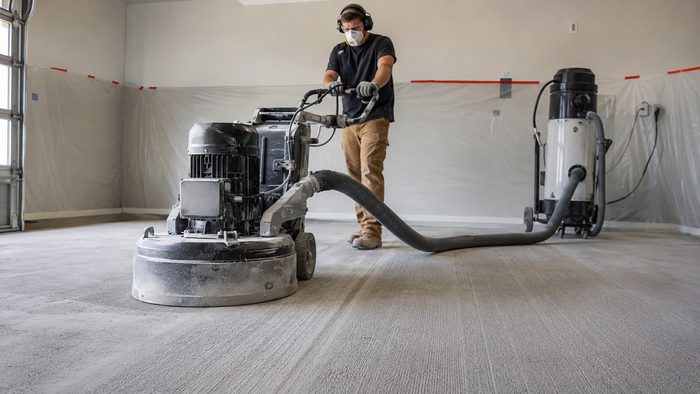 Concrete floor grinder with dust extraction preparing a slab for coating