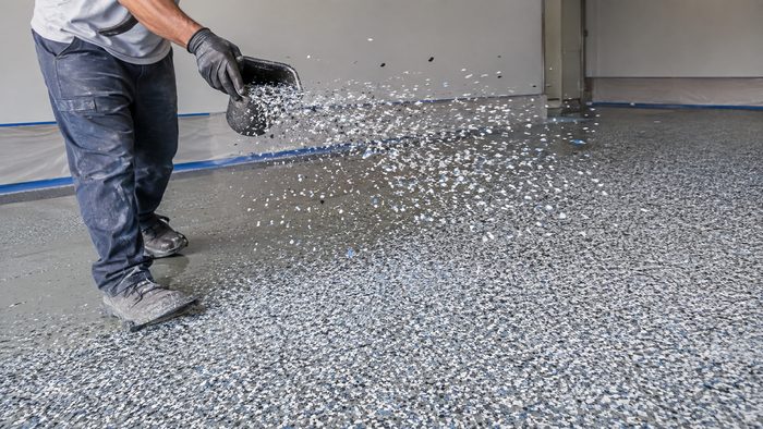 Decorative flake chips being broadcast by hand onto a wet epoxy base coat