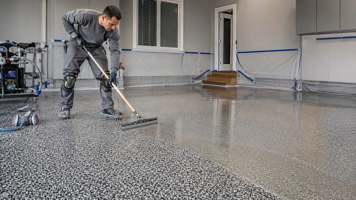 Clear topcoat being squeegeed over a grey flake broadcast floor
